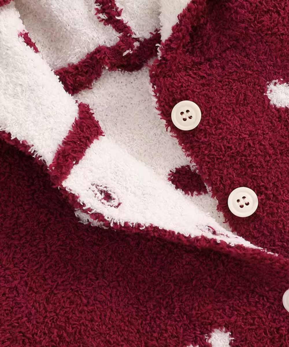 Gros plan du tissu polaire bordeaux et blanc avec boutons du poncho bébé Planète Poncho.