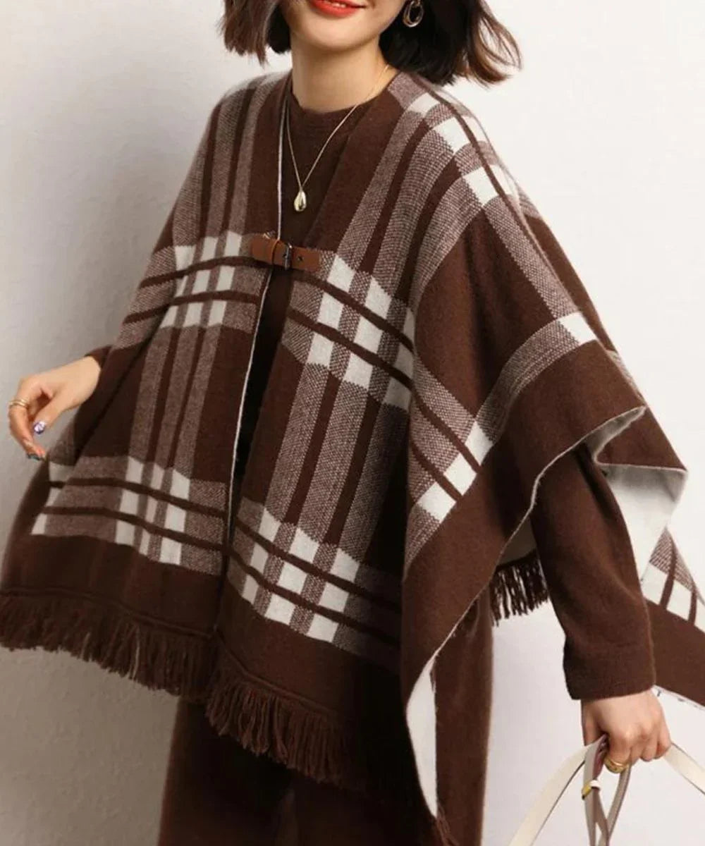 Poncho cape en cachemire marron à carreaux blancs avec franges, porté par une femme.