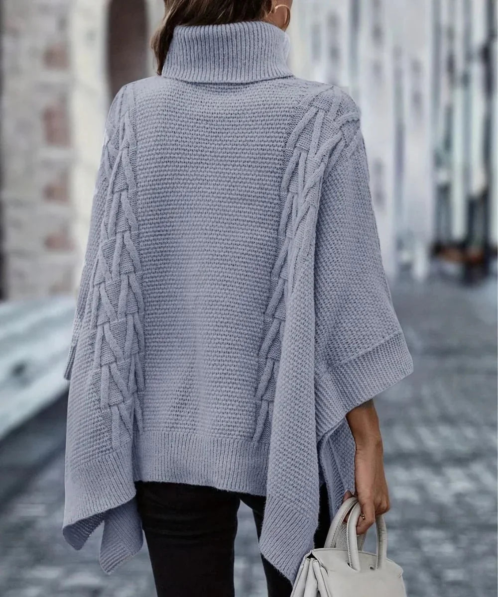 Poncho femme gris en maille avec col montant et motif torsadé, porté en extérieur