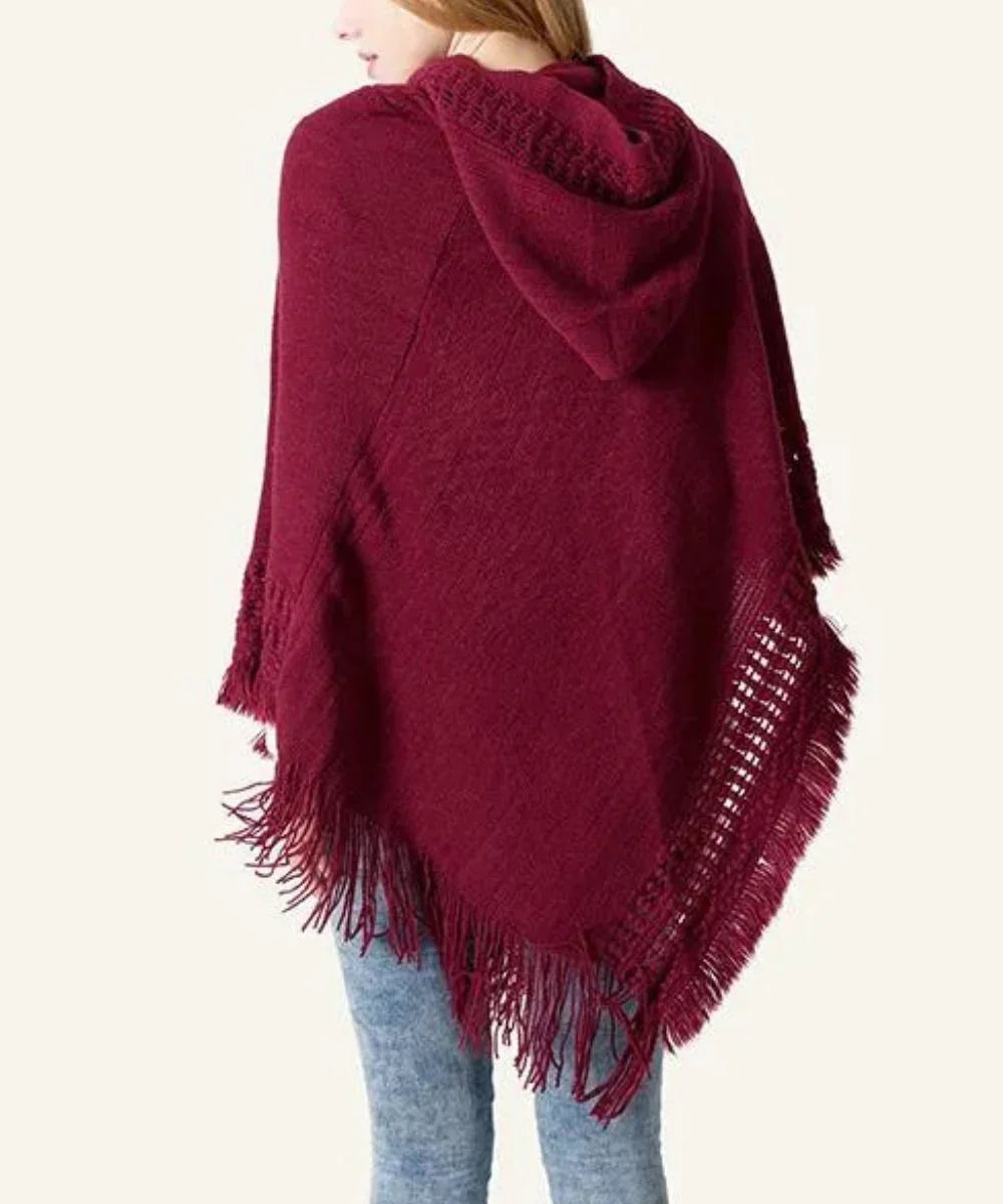 Poncho femme bordeaux à capuche et franges, porté avec un jean, fond clair
