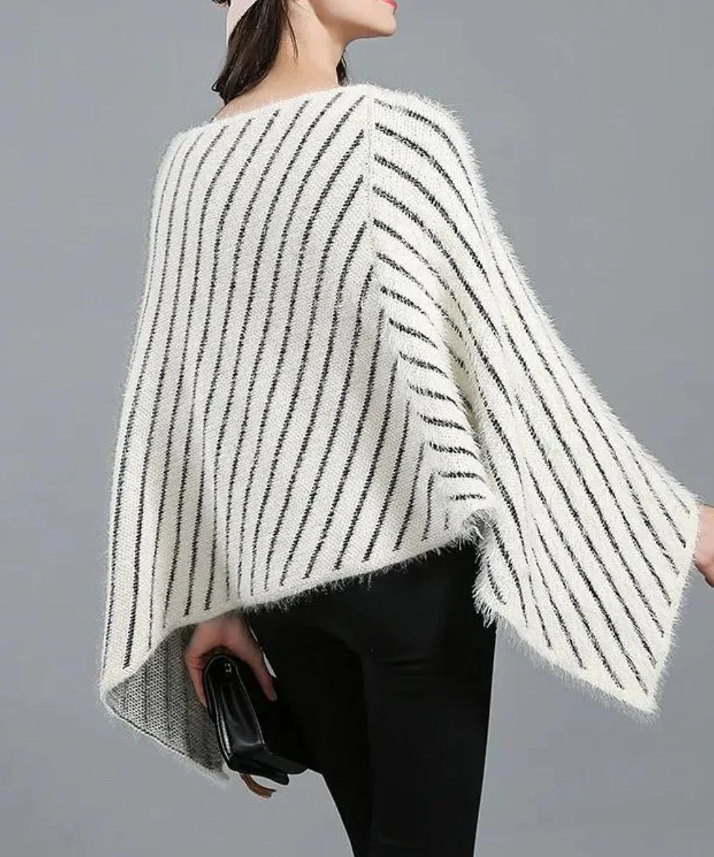 Femme portant un poncho blanc à rayures noires, tenue hivernale élégante