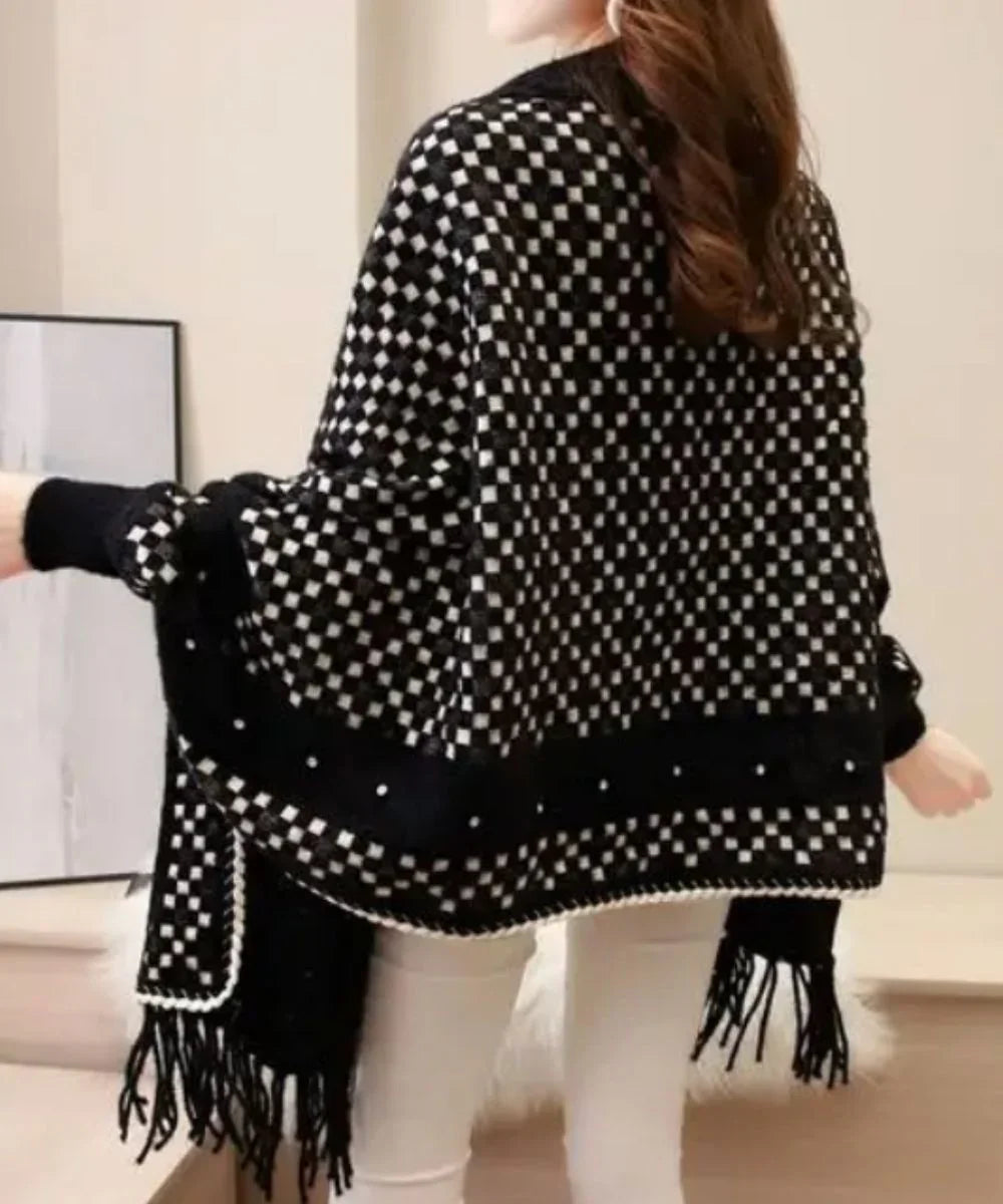 Poncho laine noir femme à motifs carrés, franges, porté en intérieur, style élégant.