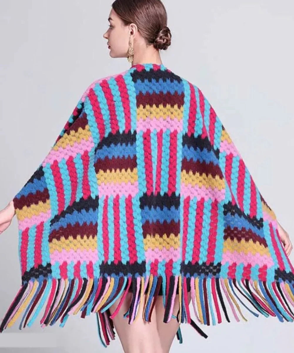 Femme portant un poncho multicolore à motifs rayés et franges, style hivernal tendance.