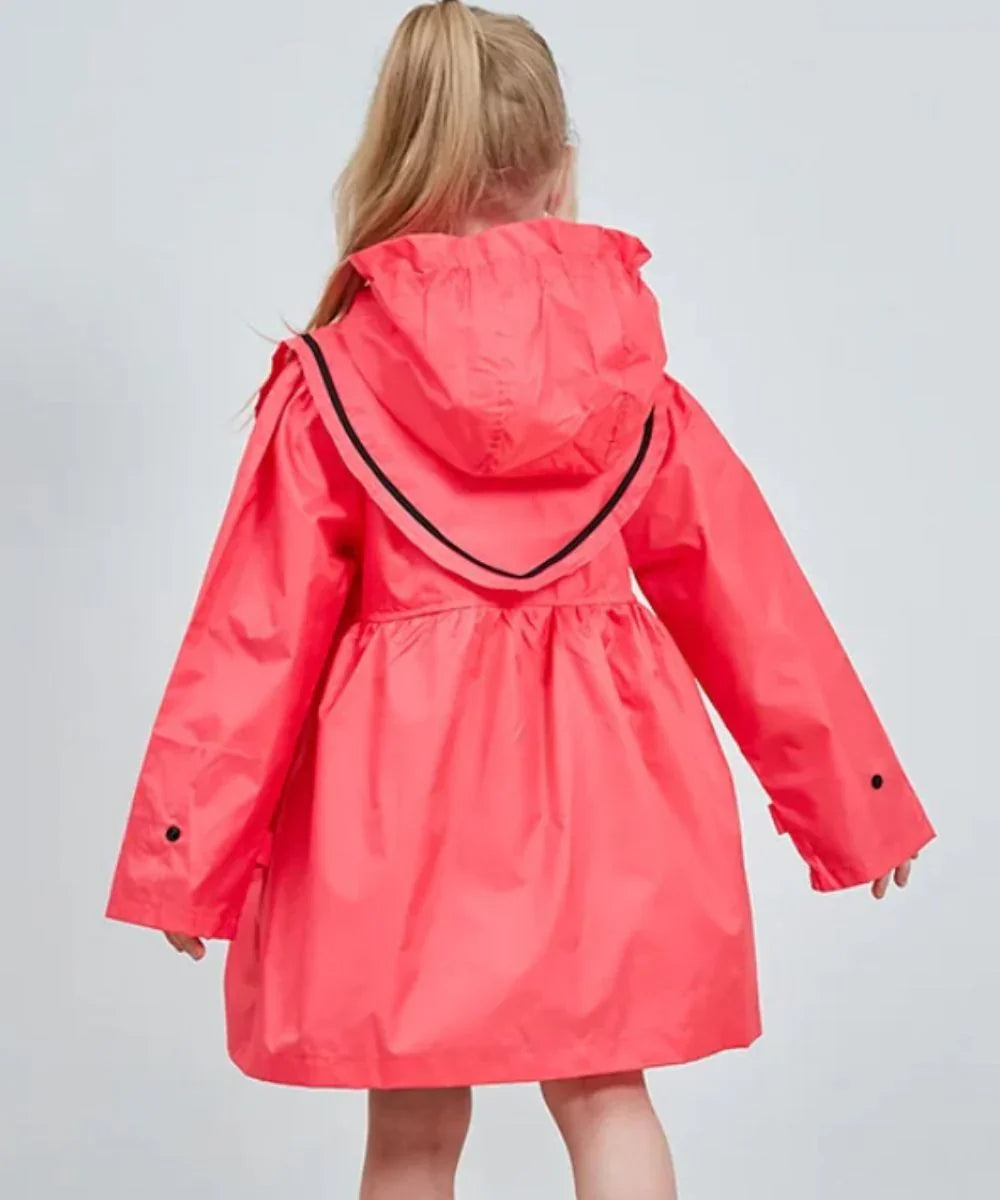 Fille portant un poncho de pluie rose à capuche, coupe ample, fond neutre.