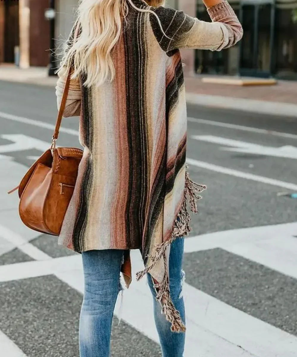Femme portant un poncho rayé à franges, avec jean déchiré et sac marron en ville.
