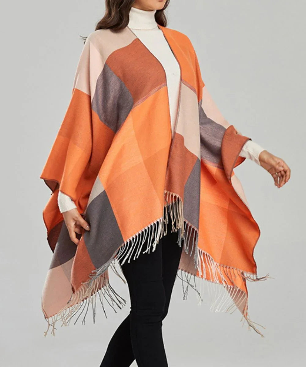 Poncho femme à carreaux orange et beige avec franges, porté sur un pull, mode automne-hiver
