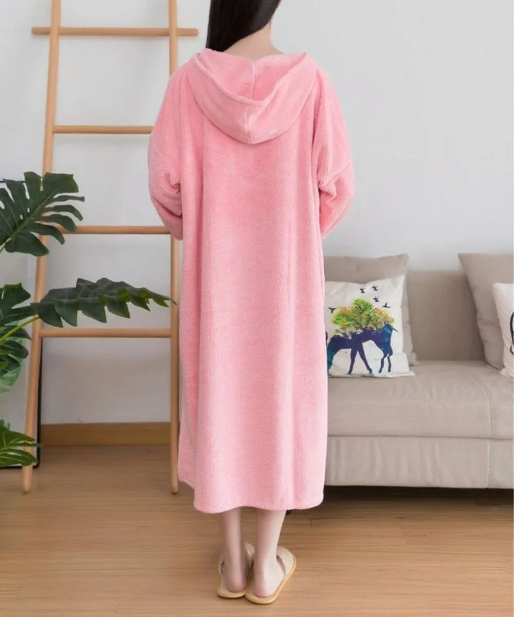 Peignoir poncho rose à capuche, femme debout dans un salon moderne, ambiance cosy