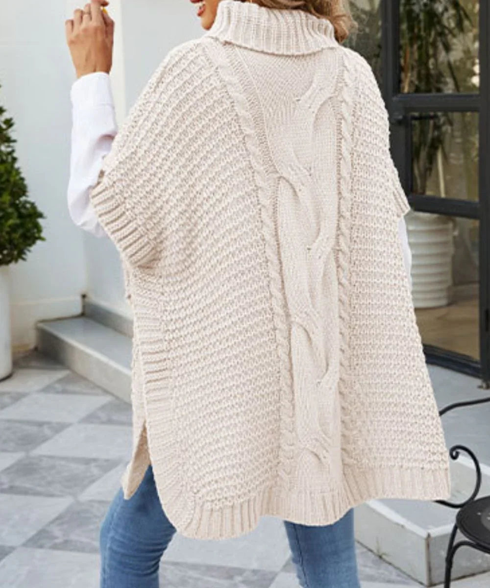 Poncho femme beige à manches, grosse maille torsadée, porté avec un jean en extérieur