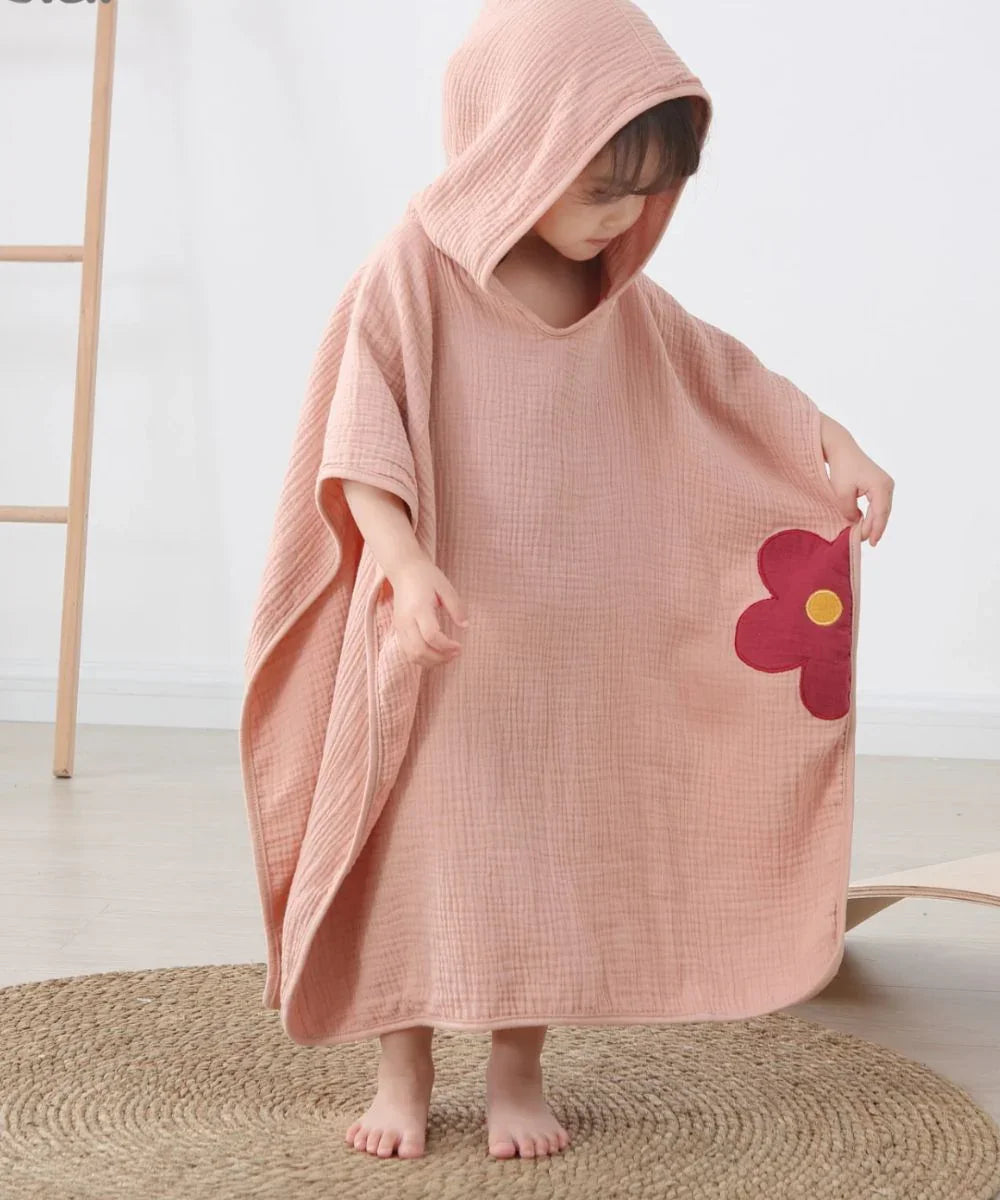 Enfant portant un poncho de bain rose à capuche avec motif fleur, poncho enfant doux.