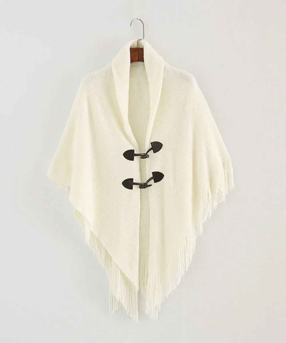 Poncho blanc à col châle, fermetures noires, fini frangé, suspendu sur fond clair