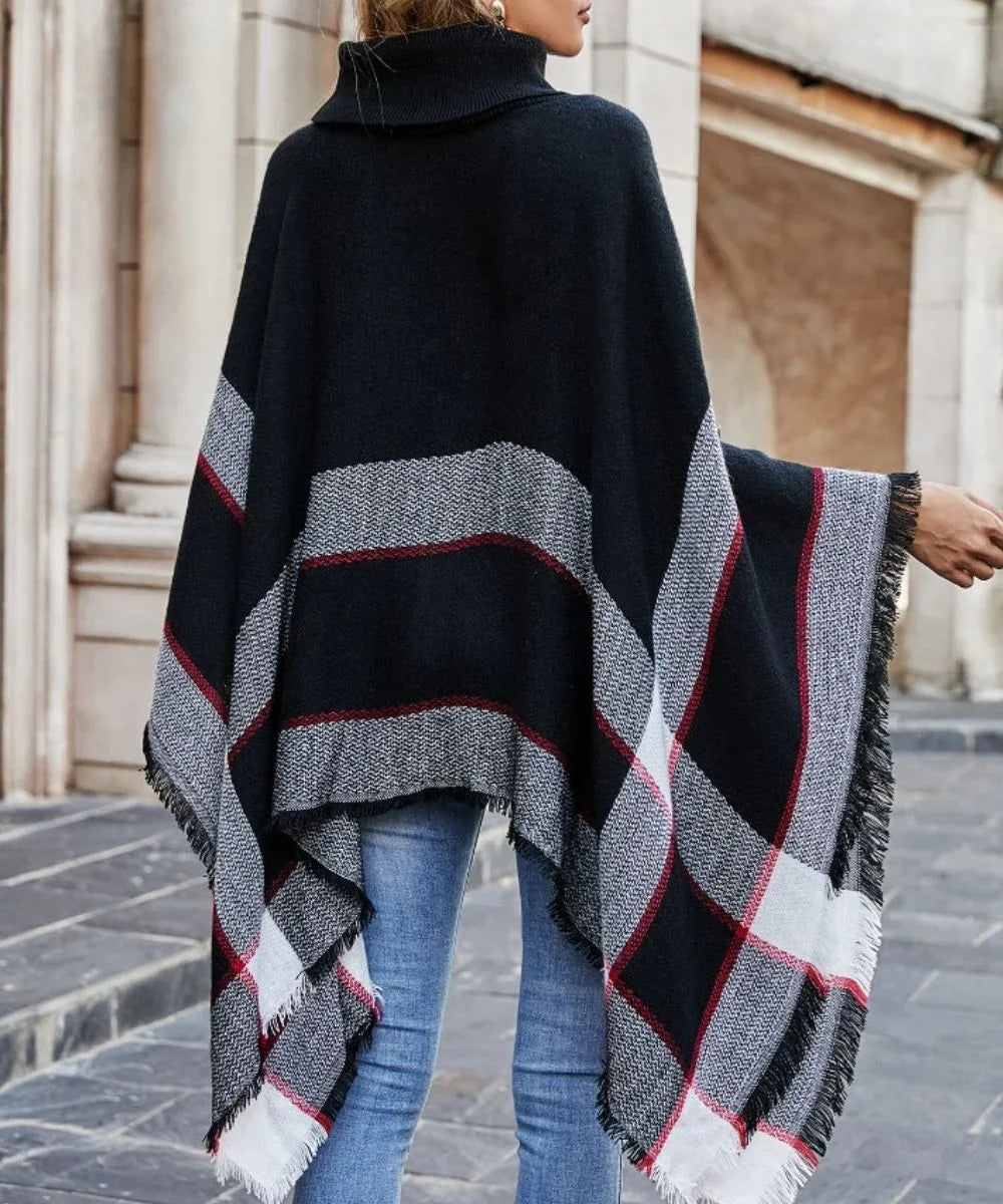 Poncho noir à col boule, motifs à carreaux rouges et gris, femme debout en extérieur