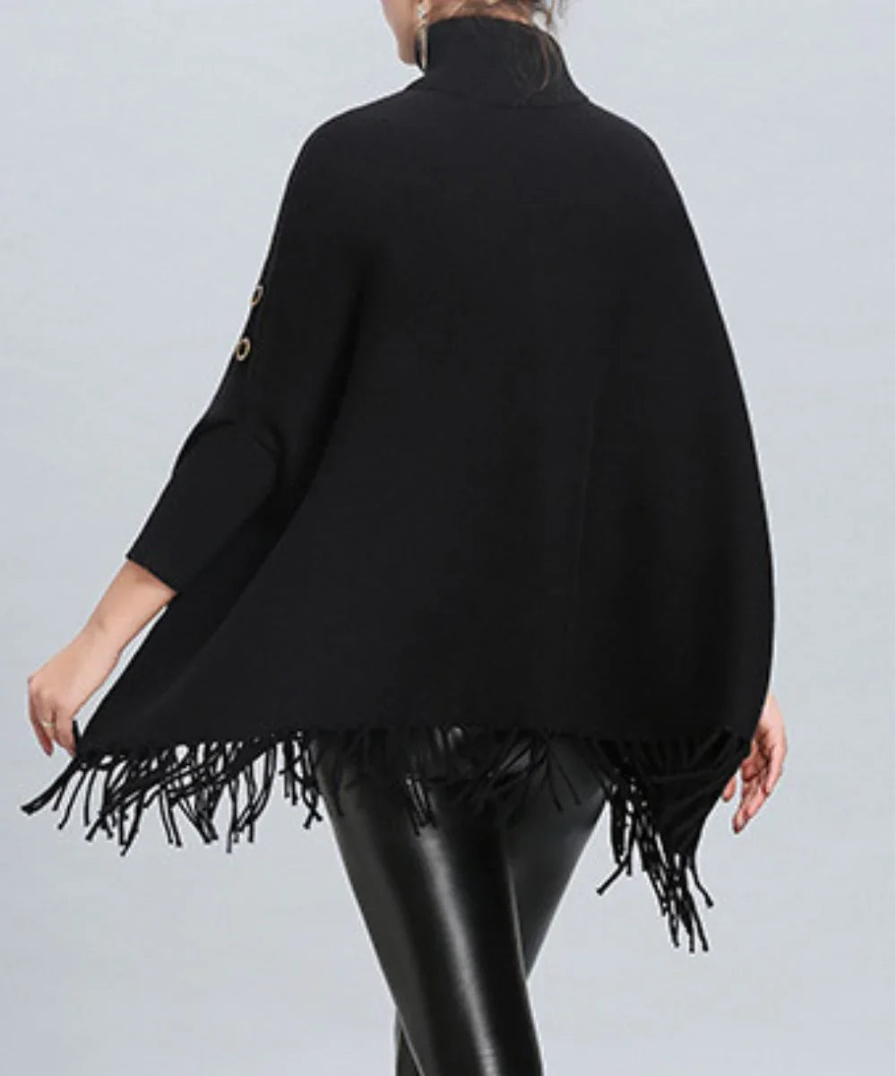Poncho femme noir à col montant, détails à boutons et franges, porté avec un pantalon en cuir