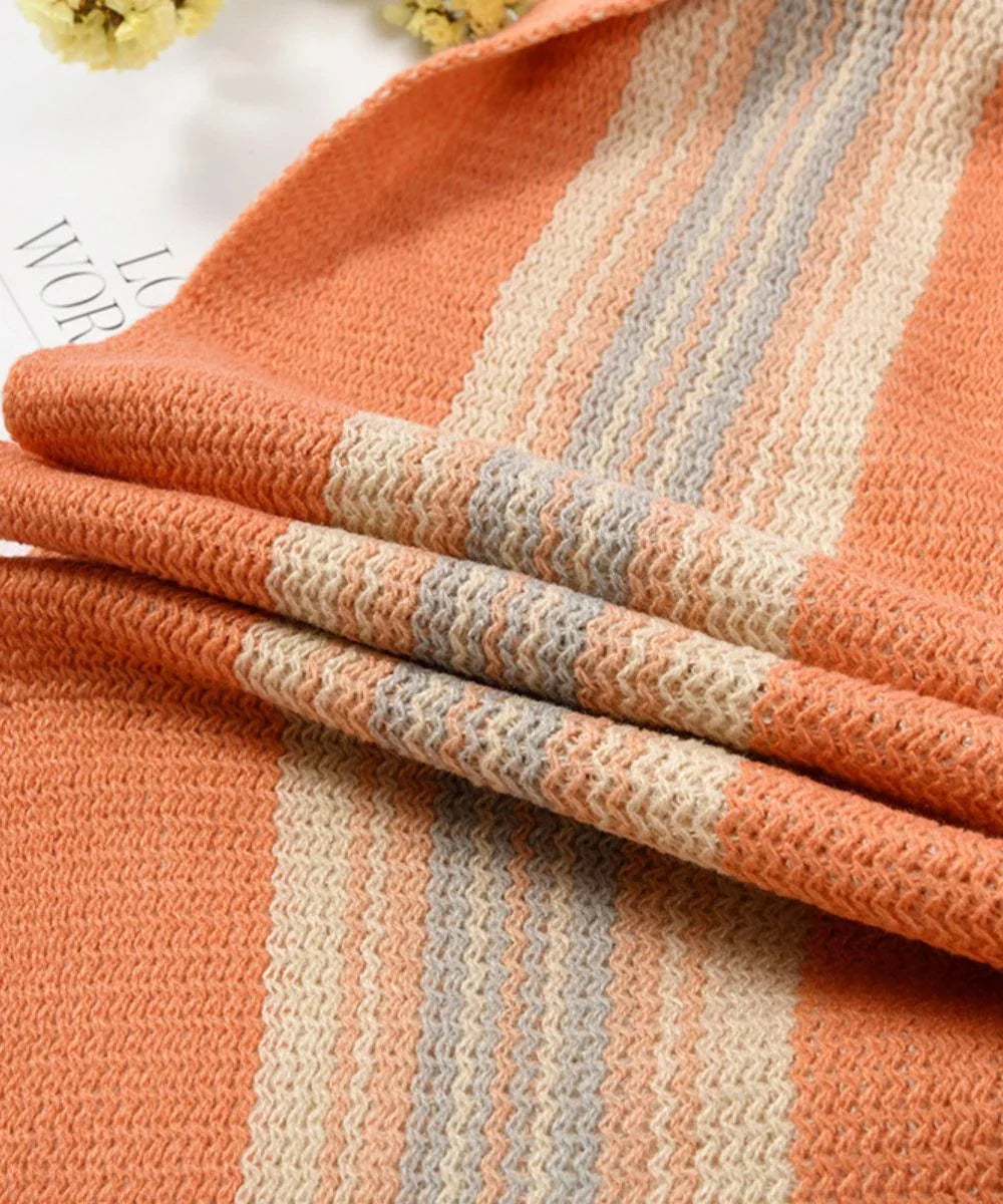 Poncho femme orange en maille rayée beige et grise, texture douce, gros plan mode.