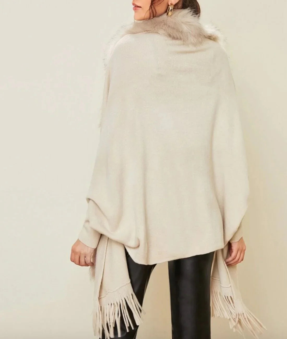 Poncho femme beige à col en fausse fourrure, franges, porté avec pantalon en cuir noir