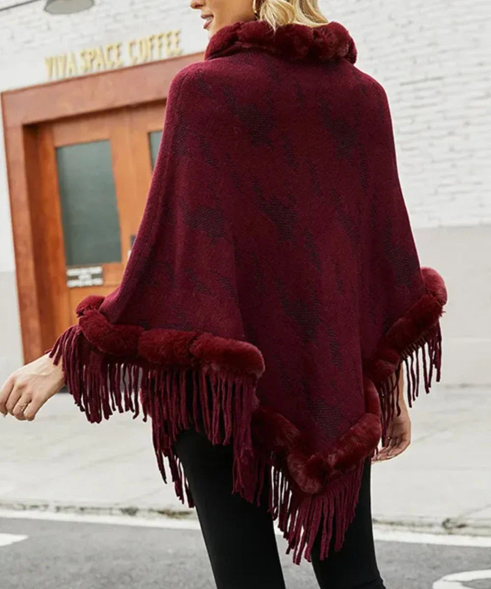 Poncho femme rouge à franges, col fourrure, porté en extérieur, style élégant hiver.