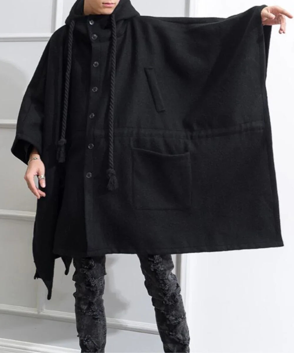 Homme portant un poncho long noir à capuche et boutons, style moderne et décontracté