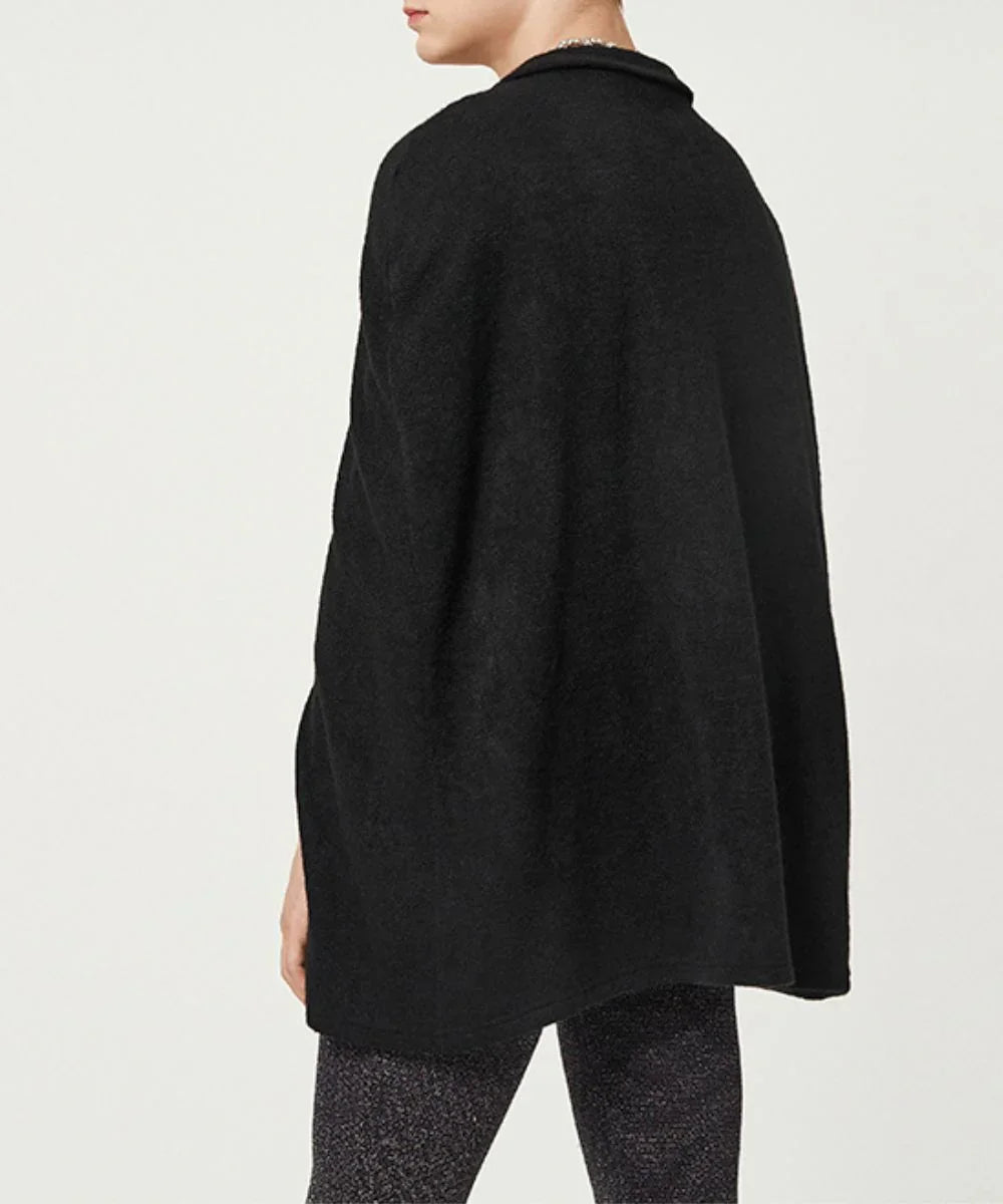 Homme portant un poncho noir uni, vu de dos, sur fond clair, vêtement décontracté.