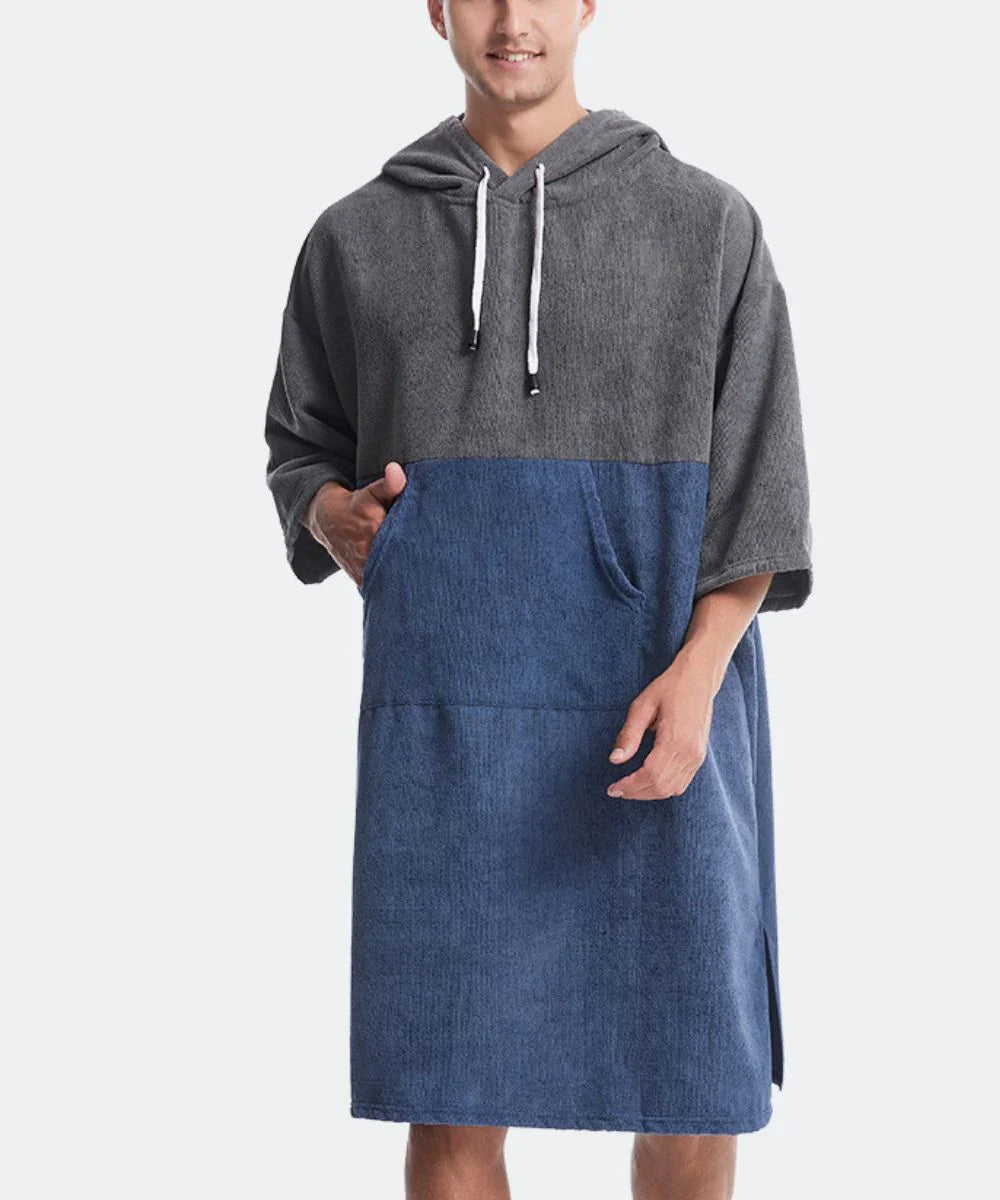 Homme portant un poncho serviette à capuche bicolore gris et bleu, coupe décontractée.