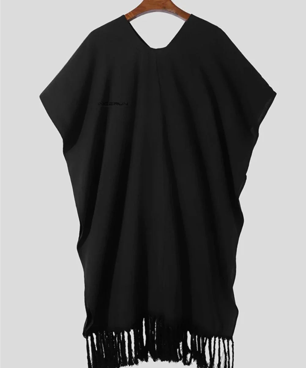 Poncho homme noir à franges, vêtement ample suspendu sur cintre, fond gris