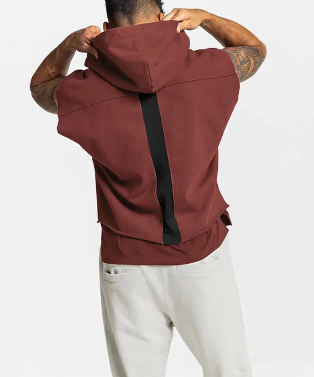 Homme portant un sweat poncho bordeaux à capuche, bande noire au dos, style décontracté.