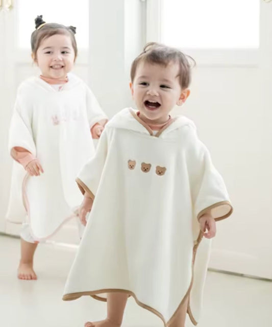 Deux bébés portant le poncho blanc unisexe à motifs de Planète Poncho.
