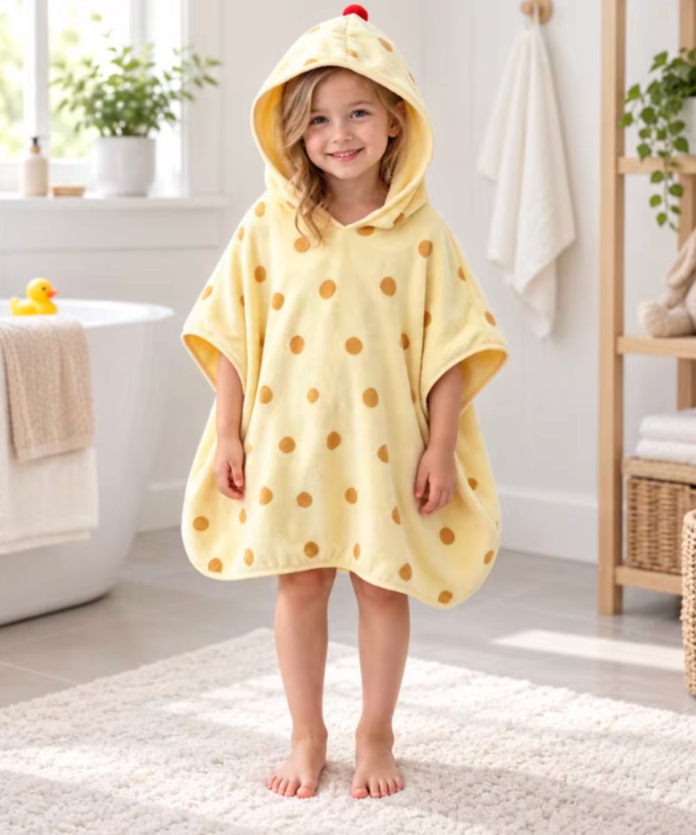 Petite fille portant un poncho de bain jaune à pois marron de Planète Poncho.