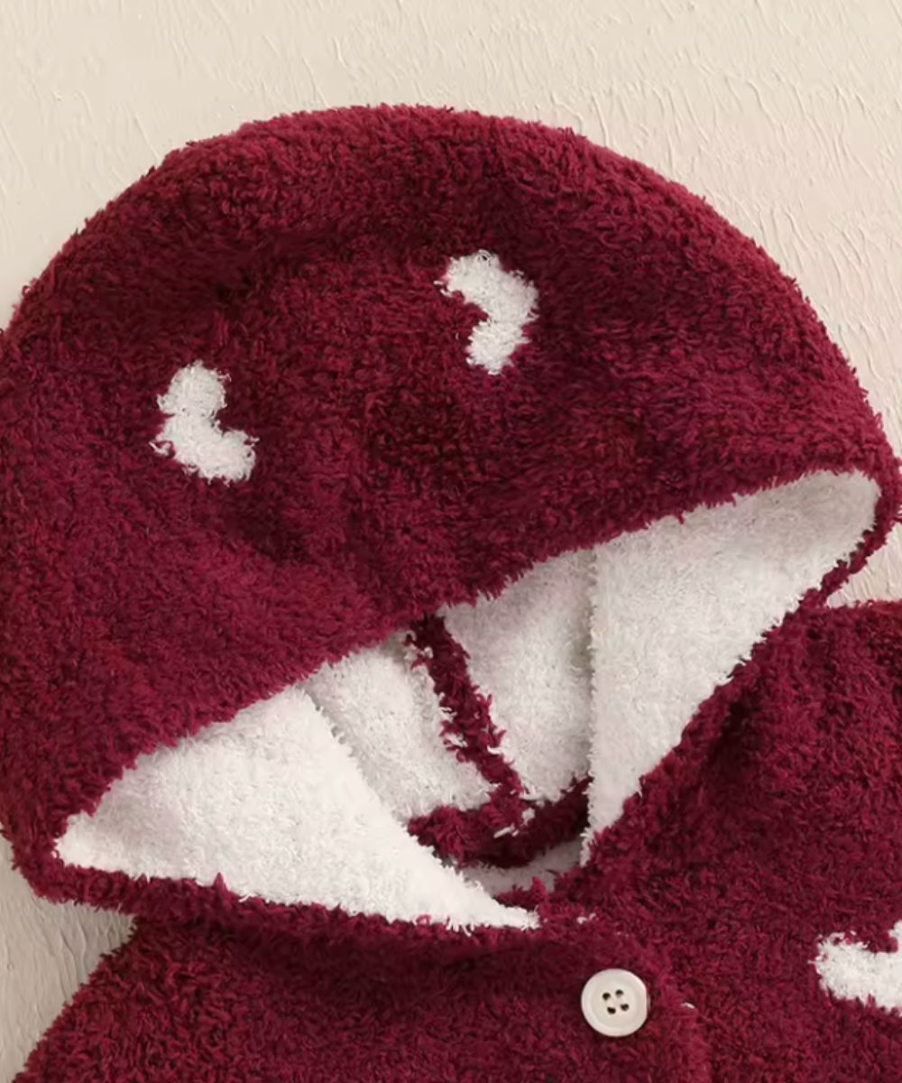 Gros plan de la capuche rouge d'un poncho d'extérieur bébé Planète Poncho avec motifs blancs.