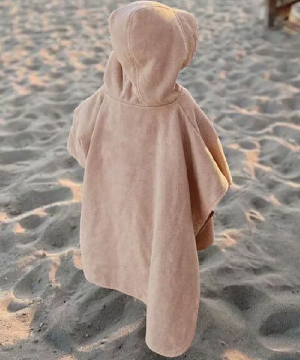 Poncho plage bébé avec capuche couleur beige sur le sable, marque planète poncho.