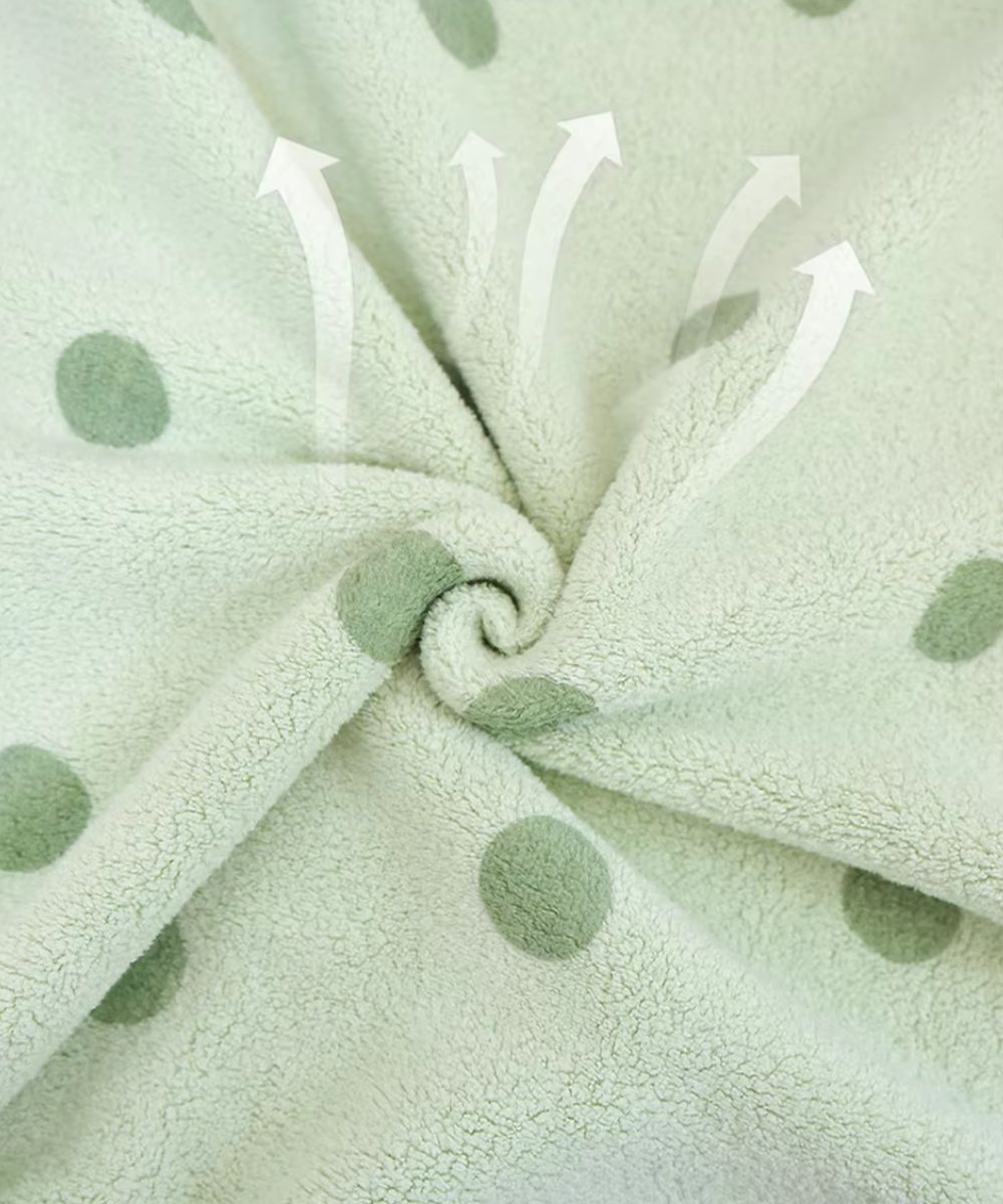 Gros plan sur la matière absorbante d'un poncho de bain bébé à pois vert pastel Planète Poncho.