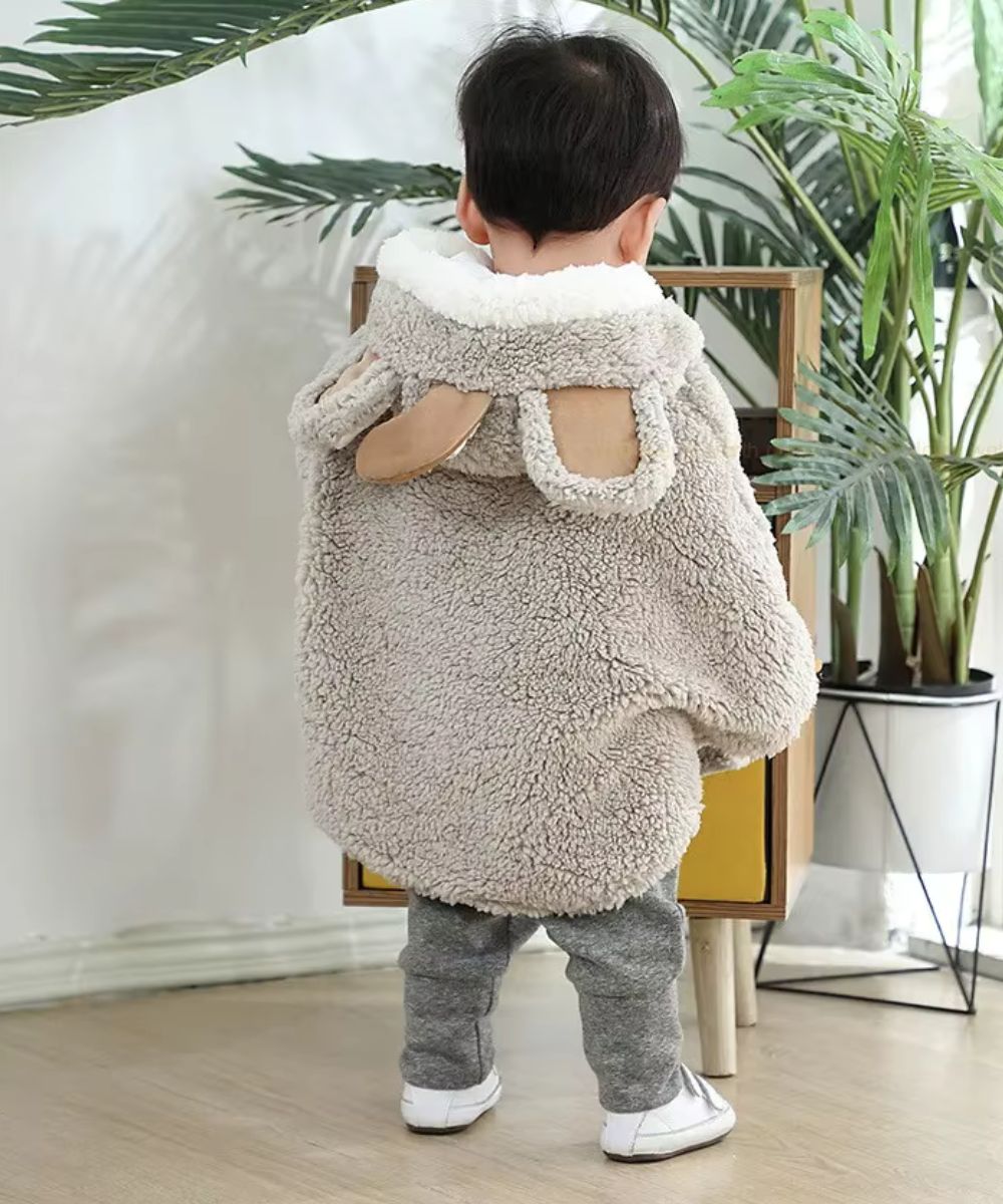 Bébé de dos portant un poncho douillet en polaire beige avec oreilles d'ours Planète Poncho.