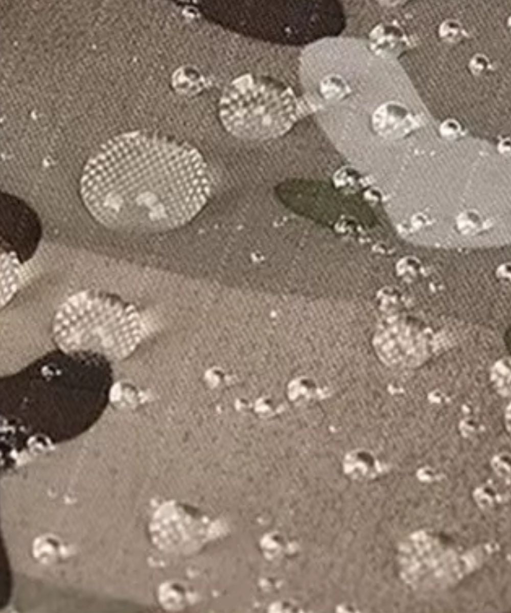 Gros plan du tissu imperméable du Poncho Pluie Tactique Planète Poncho avec gouttes d'eau.