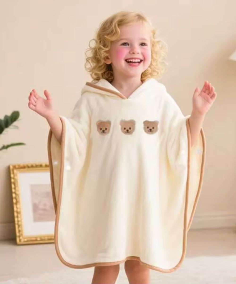 Bébé souriant portant un poncho blanc Planète Poncho avec motifs d'oursons
