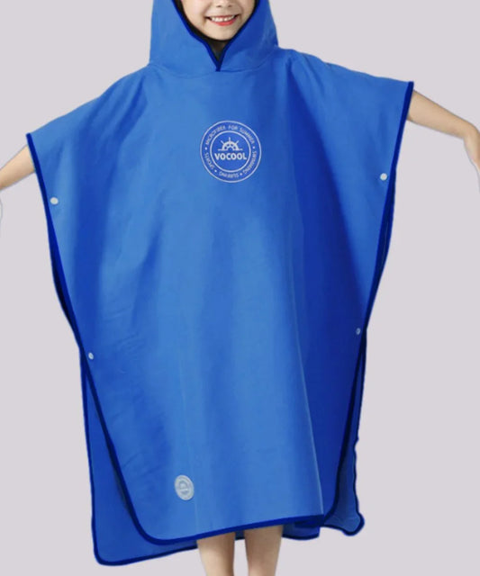 Enfant souriant portant un poncho surf bleu à capuche, adapté à la plage ou à la piscine.