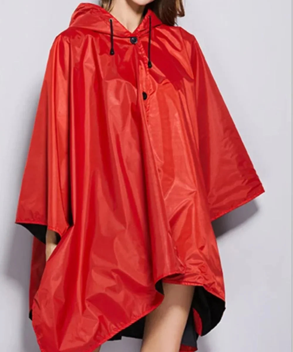Poncho de pluie femme rouge à capuche, coupe ample et tissu imperméable.
