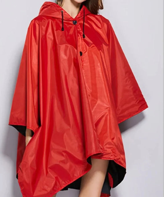 Poncho de pluie femme rouge à capuche, coupe ample et tissu imperméable.