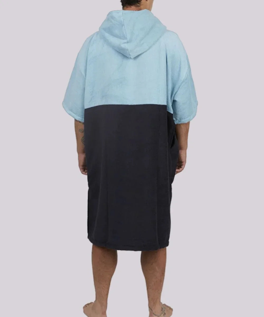Homme portant un poncho de surf hiver bicolore bleu et noir avec capuche.